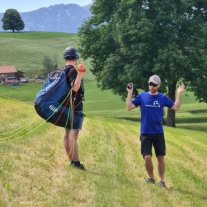 Fluglehrer von Swissgliders erklärt einem Schüler mit Gleitschirmleinen die Handhabung auf einer Wiese